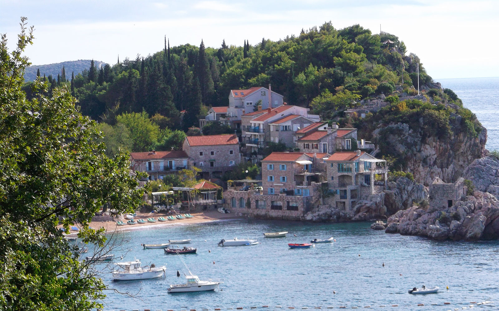 Pržno beach and harbour, fine pebble shore with apartments and the Bay of Kotor mountains behind, Montenegro