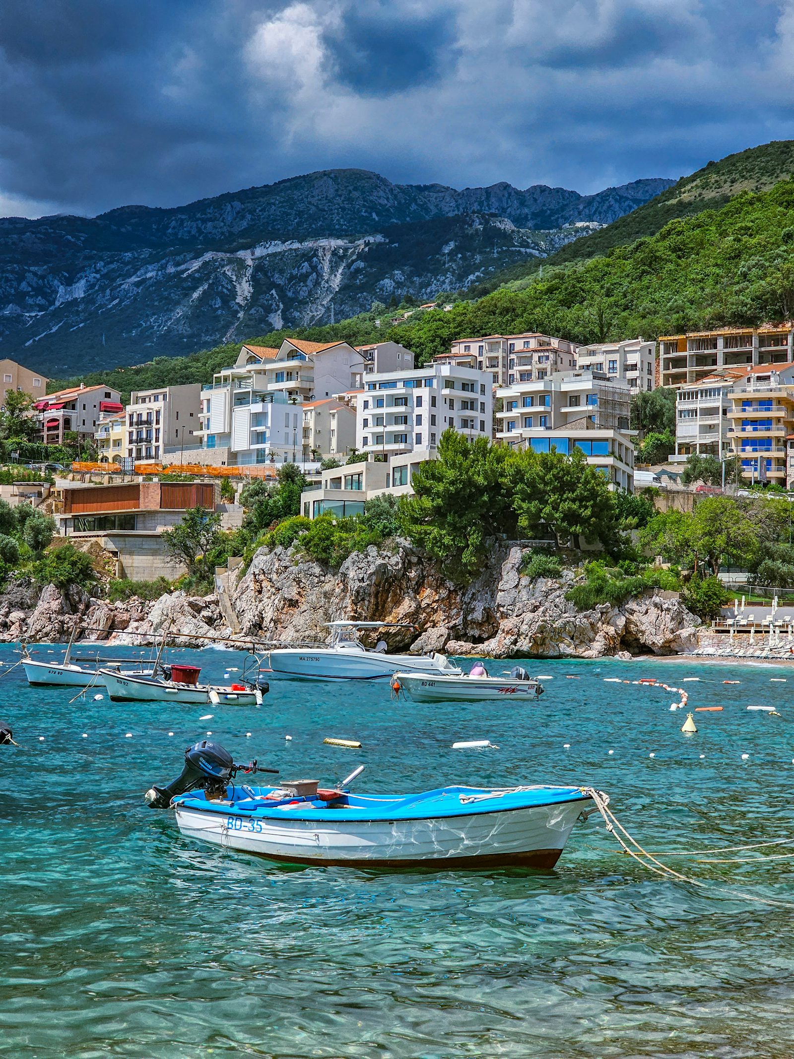 Fishing boats moored in Pržno harbour with apartments and mountains behind, Montenegro